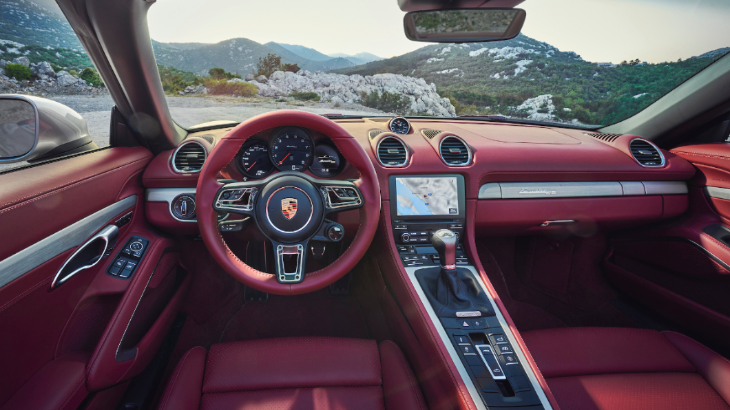 Boxster 25週年紀念車大量採用酒紅色真皮、髮絲紋鋁合金內裝飾板套件等，營造出運動感。(圖片來源/ Porsche)