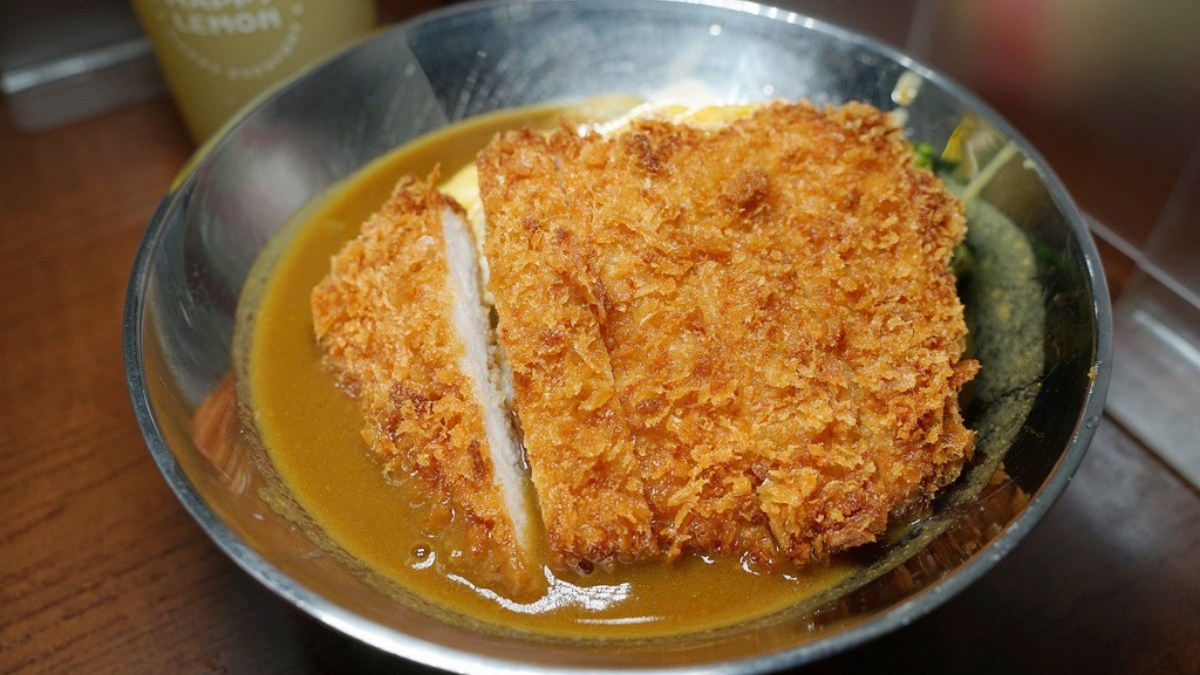 咖哩飯是用不銹鋼碗來裝，上頭的炸豬排滿大片。（圖片來源：東蛙池塘）