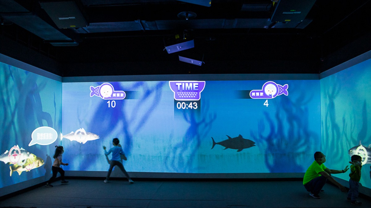 投影螢幕會出現紅色、藍色魚群，只要靠近揮手就能捕捉到魚。（圖片來源：史努比遊樂園）