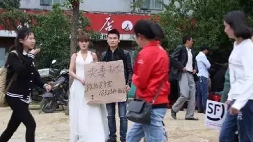 安徽合肥有男子在大街上高舉「賣妻救女」的牌子，吸引路人關注。（圖／翻攝自網易新聞） 人父大街高舉「賣妻救女」　老婆穿婚紗等出價