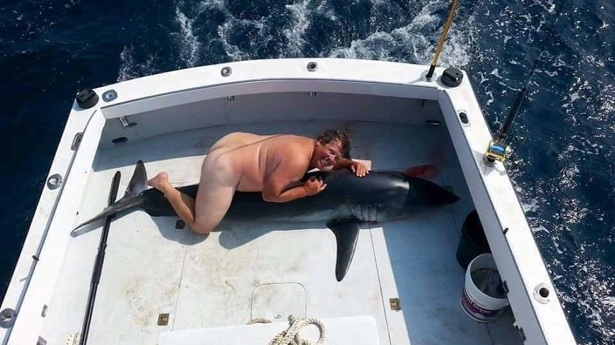 這名全裸肥男趴在一隻死掉的鯊魚身上，引發網友眾怒，揚言要將他肉搜出來。(圖／翻攝自推特)