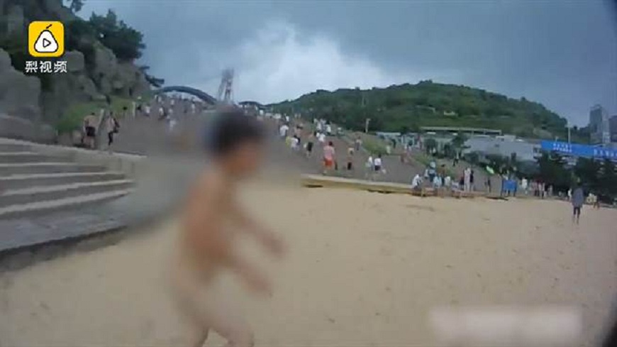 江蘇一名大媽因孩子讓她玩水不成，當場在沙灘上脫掉泳衣裸奔。(圖／翻攝自梨視頻)