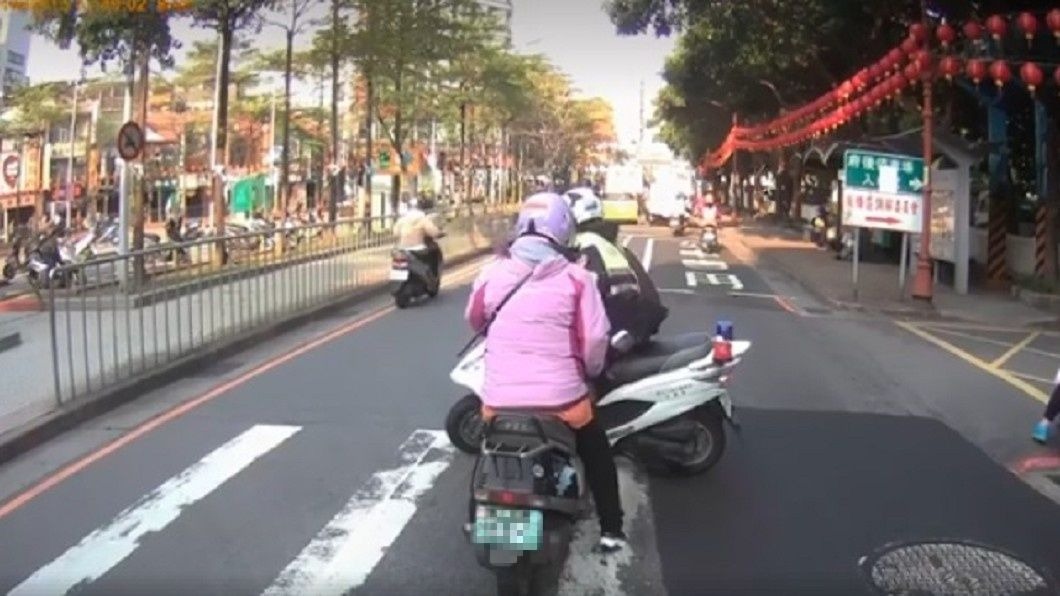 員警肉身擋車的動作，為的是要幫助一名行動緩慢的婦人過馬路。圖／翻攝自臉書《重機車友▕ 各區路況、天氣回報中心》