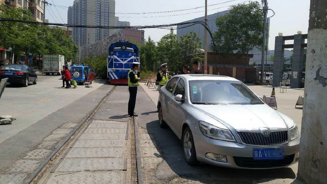 一名車主將車停在社區門口,卻逼停一輛經過的火車。圖/翻攝自華商網