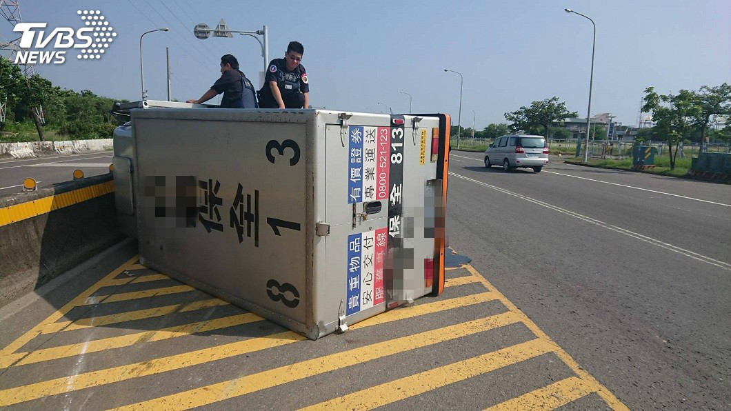 一輛運鈔車行經高雄興達港一處彎道時不慎翻覆，保全人員連忙爬出戒護。(圖／TVBS)