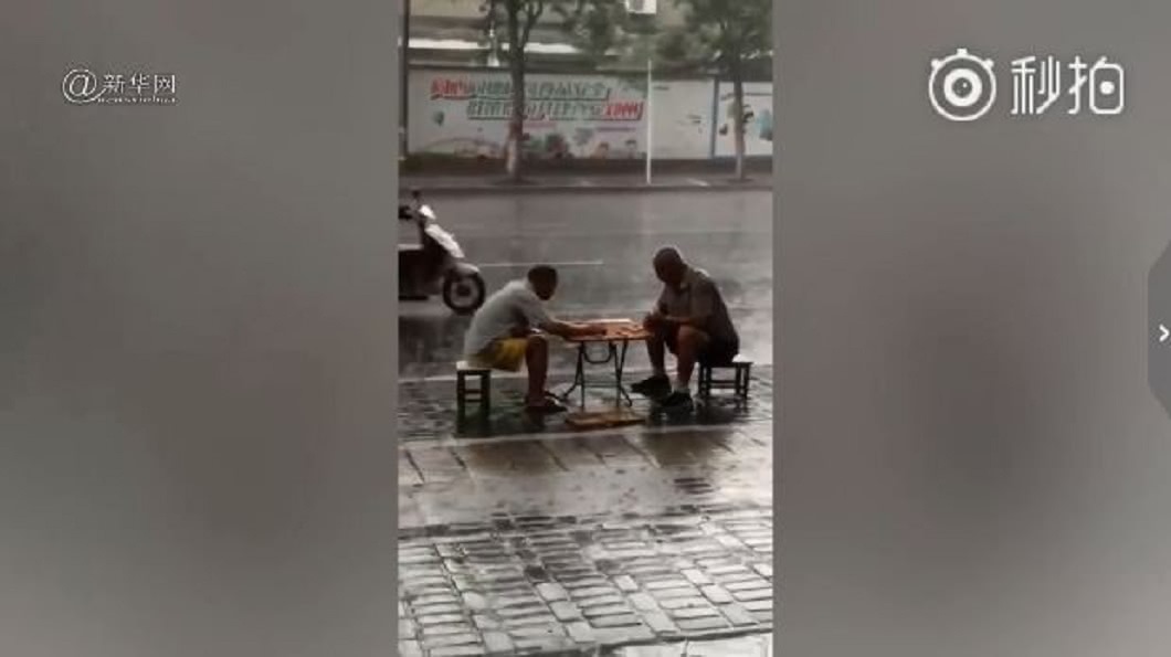 河南街頭有2位大叔在雨中下棋，引發網友熱烈議論。(圖／翻攝自微博)