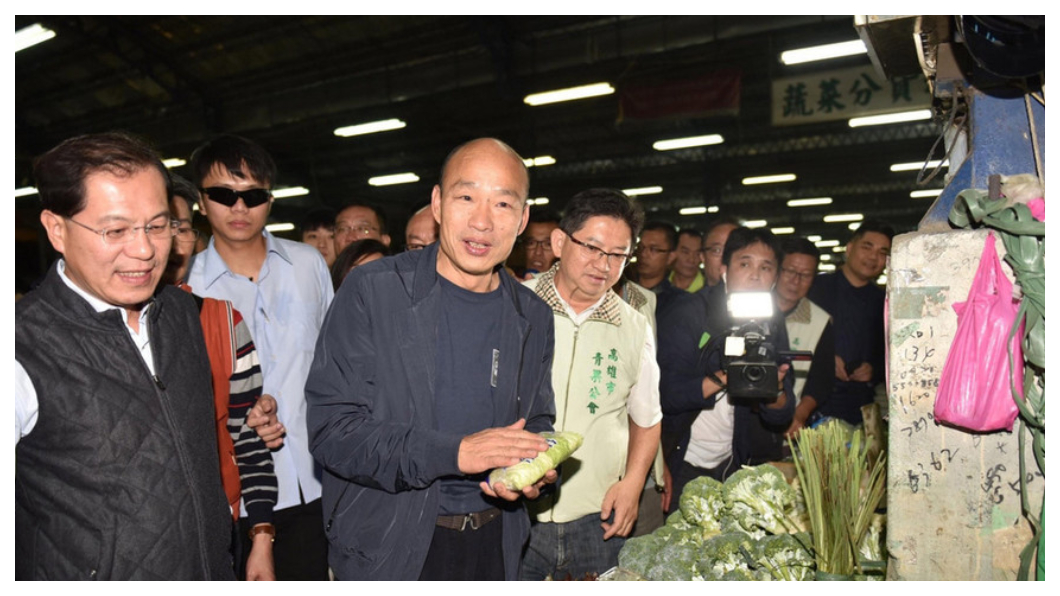 高雄市長走馬上任第一天,韓國瑜(左三)夜宿高雄十全果菜市場,緊跟在旁、邊聽邊做筆記的人,是高雄新任農業局長吳芳銘(左一)。距離他們宣布就任新職的時間還不到24小時,他們隨時已在掌握攤商心聲、農產運銷「價」與「量」的供需。 圖/中央社