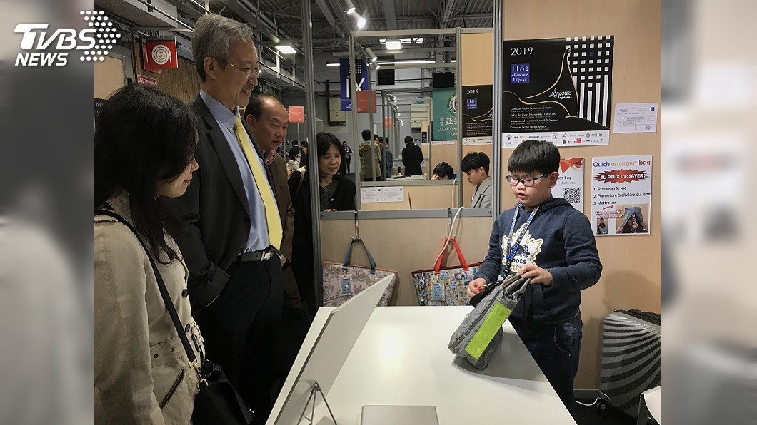 小學4年級的李國睿(右)與同學一起發明「防災妙提 袋」,親自來到巴黎雷平發明展,向駐法代表吳志中( 左2)說明產品,毫不怯場。圖/中央社