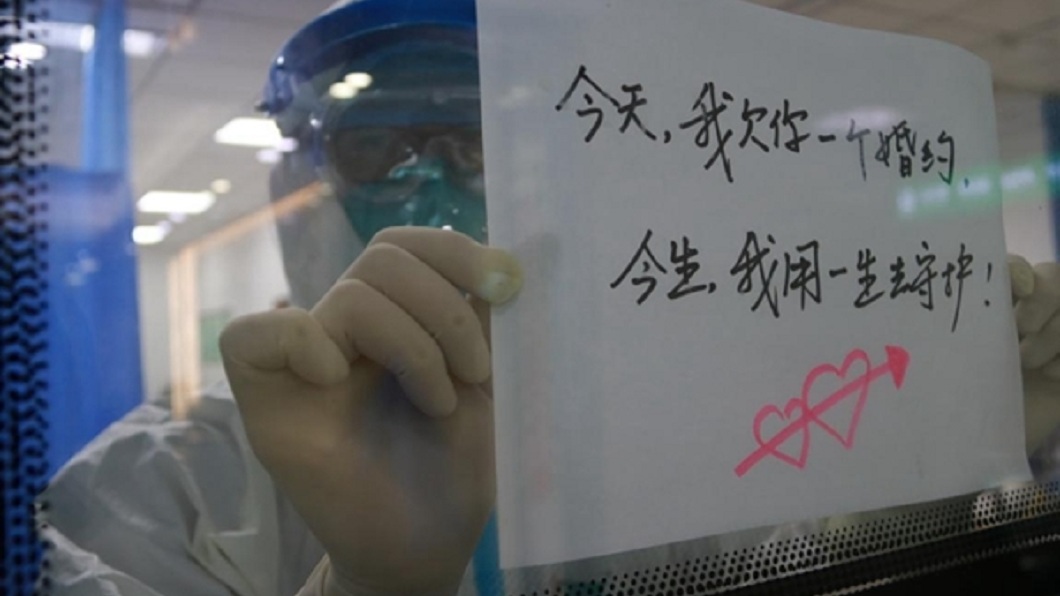 四川1名醫師投入防疫而錯過和妻子的婚禮，他寫下字條隔著隔離區的玻璃窗向對方致歉。(圖／翻攝自四川在線)