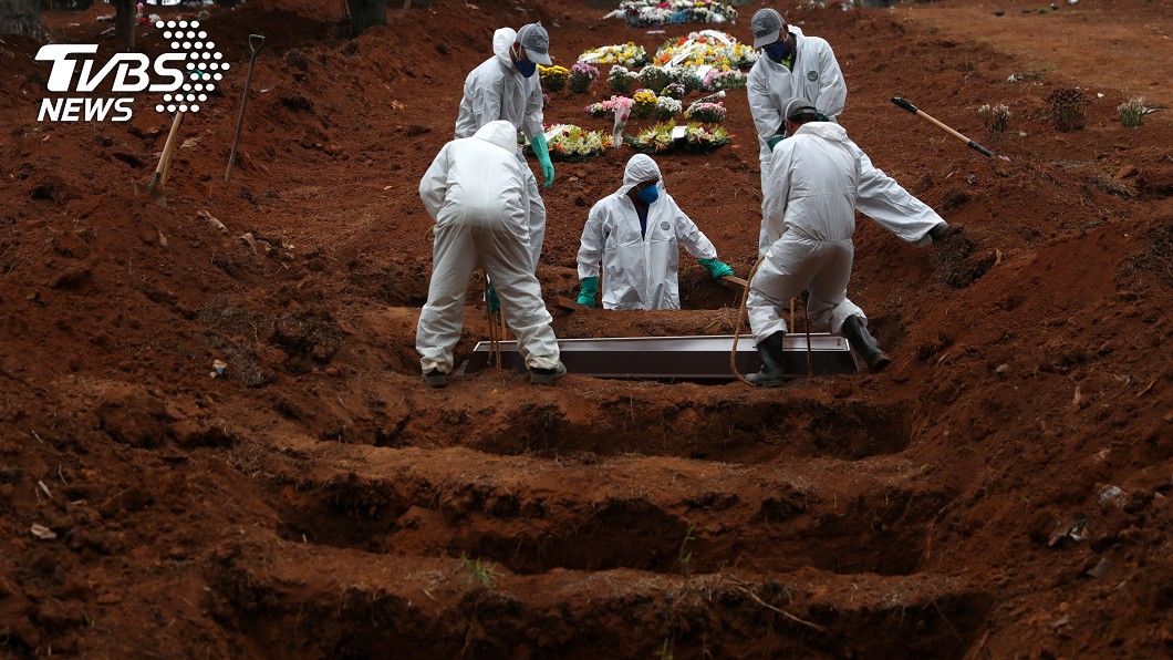 穿著防護衣的人正在埋死於新冠肺炎的死者的棺材。（圖／達志影像路透社）