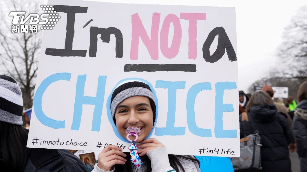 一名反墮胎抗議人士裝扮為嬰兒，並高舉標語寫道「我不是一個選擇」。（圖／達志影像路透社）