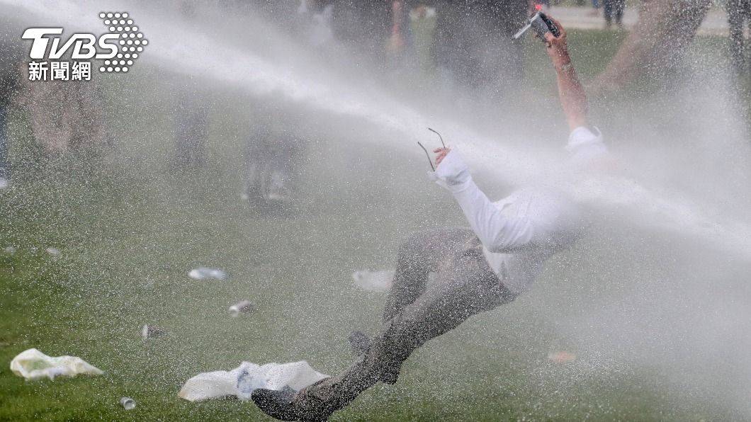 警方噴灑強力水柱驅趕抗議民眾，一名示威者遭沖倒在地。（圖／達志影像路透社）