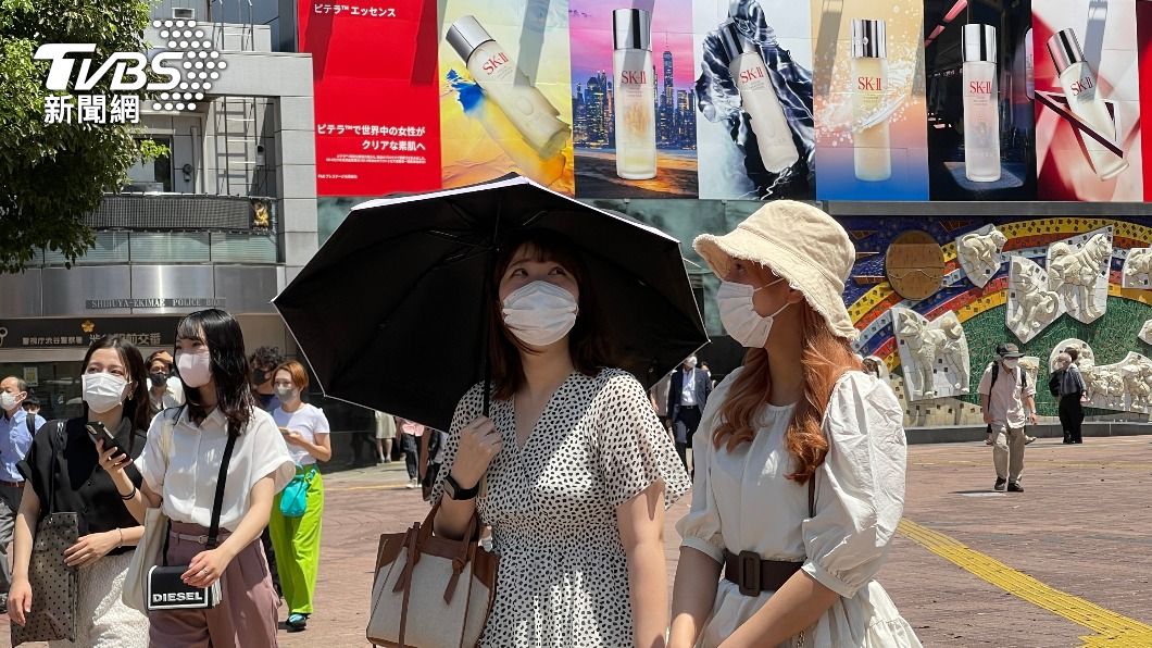 東京都JR澀谷車站前的行人撐陽傘、戴帽子防豔陽。（圖／中央社）