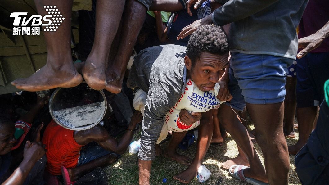 海地7.2強震過後物資缺乏，一男子搶到卡車上的白米後，緊抱住滿臉猙獰爬離現場。（圖／達志影像美聯社）