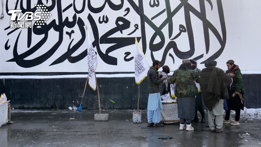 塔利班戰士向街頭小販購買旗幟。（圖／達志影像美聯社）