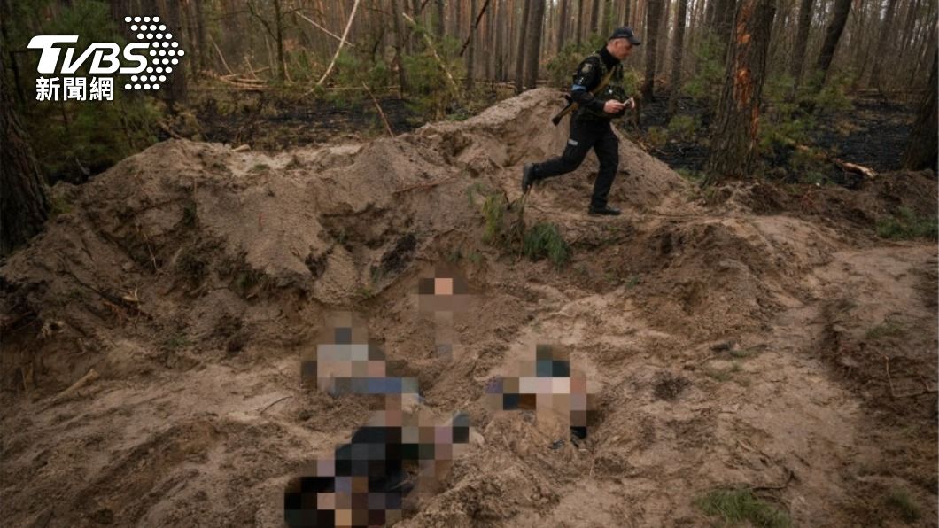 一名烏克蘭警察行經莫季任鎮鎮長一家陳屍的沙坑。（圖／達志影像美聯社）