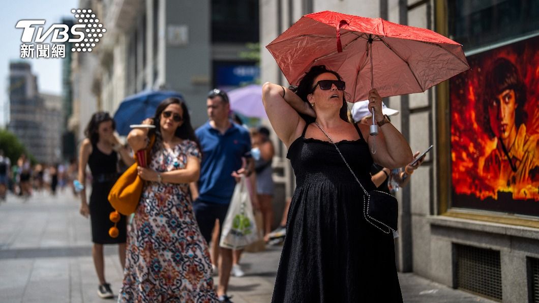 西班牙馬德里民眾受不了高溫打起陽傘遮陽。（圖/達志影像美聯社）