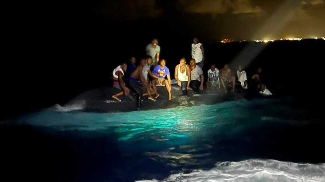 落難的海地移民坐在翻覆船隻上。（圖／翻攝自Royal Bahamas Defence Force臉書）