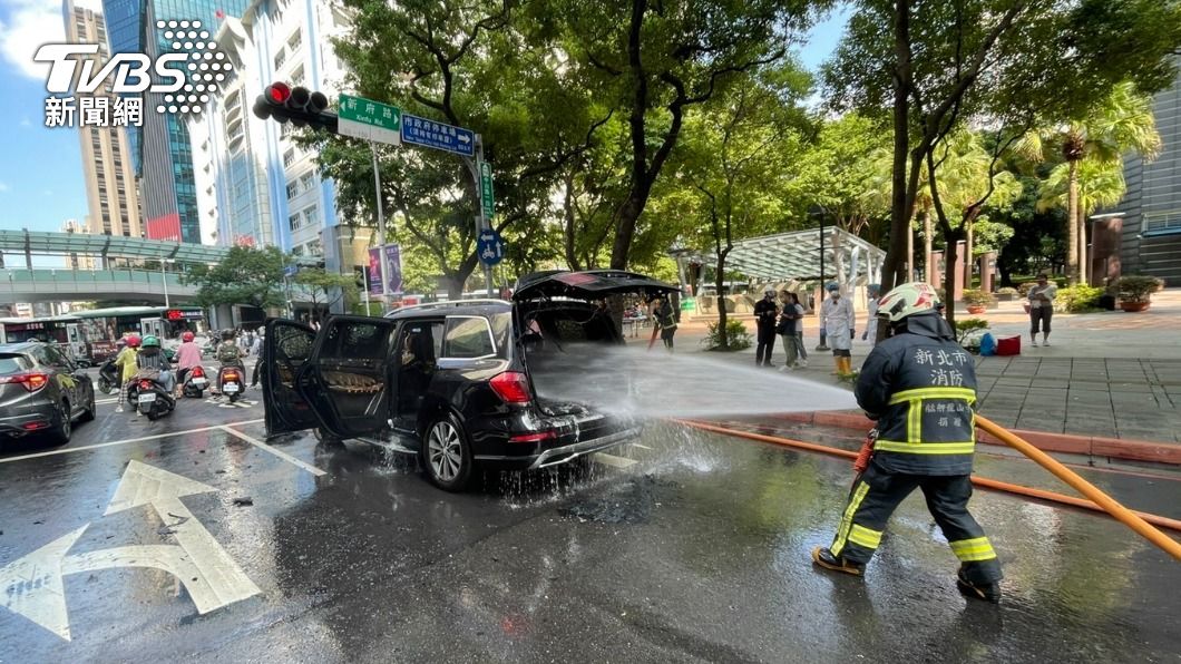 賓士車行駛在板橋市區時突然起火燃燒，消防人員射水灌救。（圖／TVBS）
