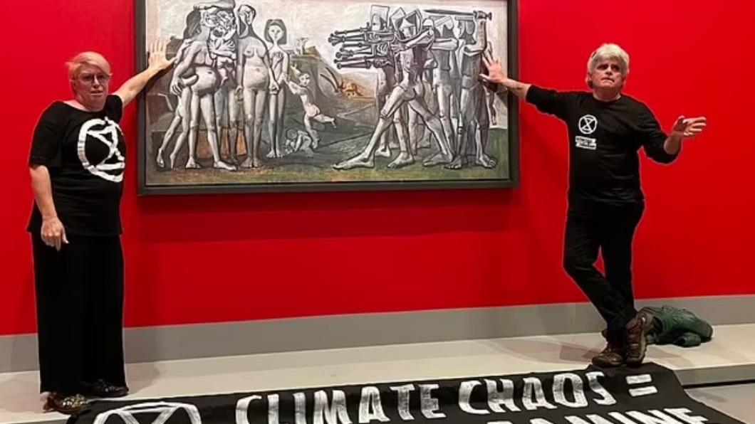 2名氣候運動者今（10）日將自己的手「黏在」畢加索知名畫作《朝鮮大屠殺（Massacre in Korea）》上，期盼喚起人們對環境問題的關注。（圖／翻攝自《每日郵報》）