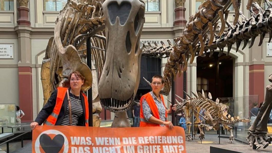 2名環保團體「最後一代」（Last Generation）成員，30日前往德國首都柏林（Berlin）自然博物館，將自己黏在擁有6千萬歷史恐龍骨架下方的支柱上。（圖／翻攝自《紐約郵報》）