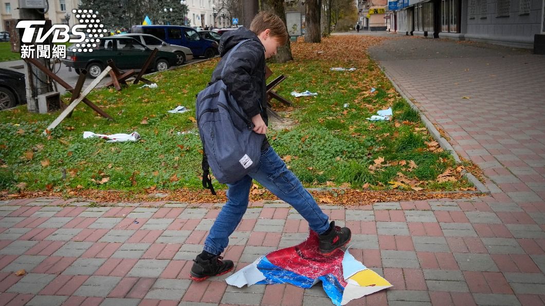 烏軍奪回赫爾松後，一名少年用腳踩踏俄羅斯國旗。（圖／達志影像美聯社）