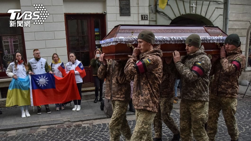 軍人將曾聖光的棺木抬至大街上，一旁烏克蘭民眾舉者中華民國及烏克蘭的國旗送別。（圖／達志影像路透）