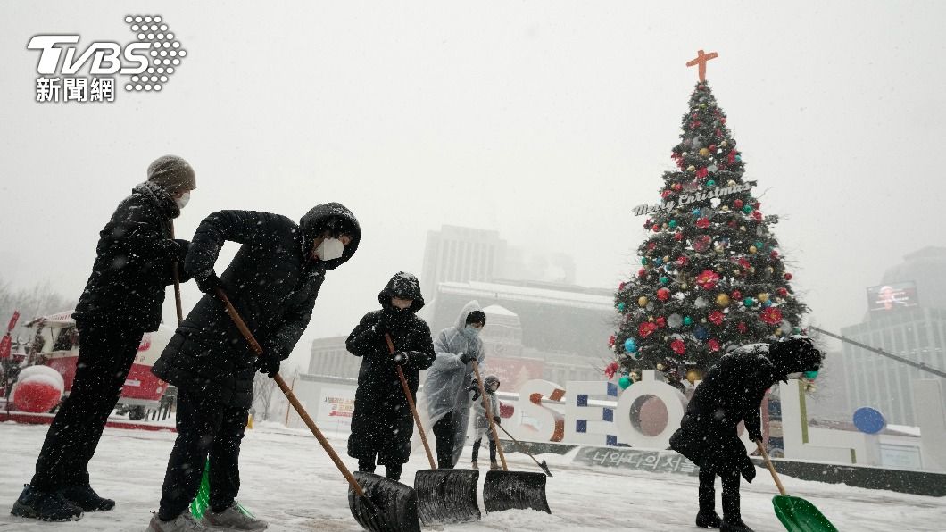 南韓受寒流影響成雪白世界，首爾民眾在市政廳旁廣場鏟雪。（圖／達志影像美聯社）
