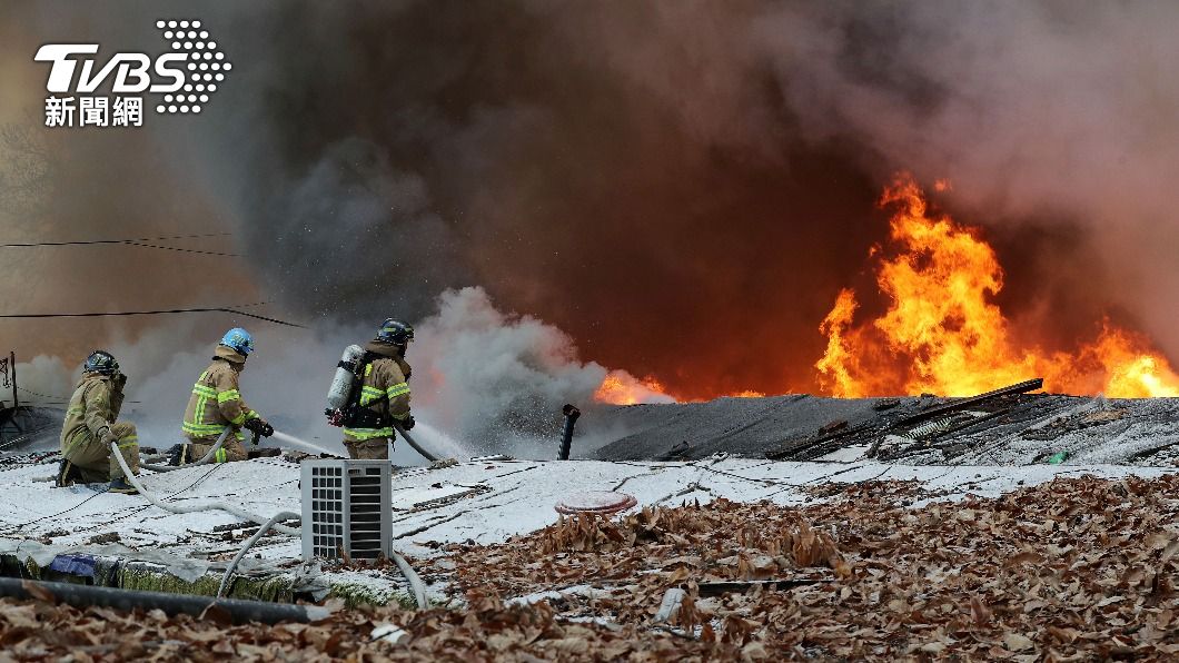 首爾貧民窟「九龍村」發生大火，消防隊員攀上屋頂，朝火苗灌注水柱。（圖／達志影像美聯社）