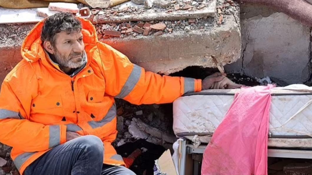 土耳其卡拉曼馬拉斯（Kahramanmaraş）一位父親，被拍下坐在殘磚斷瓦邊「緊牽著女兒的手」。（圖／翻攝自《每日郵報》）