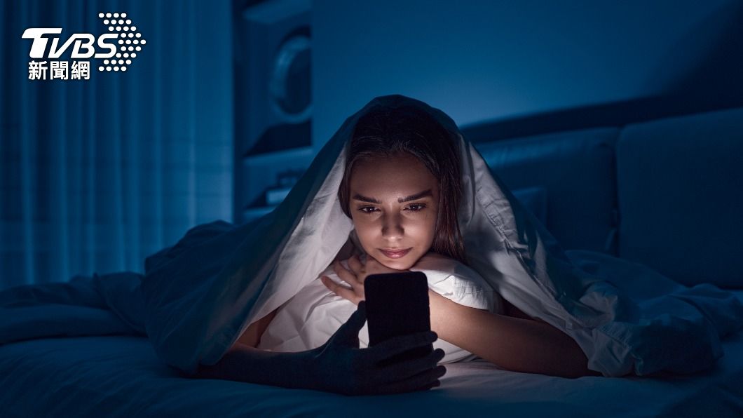 許多人明明已經關燈準備睡覺，卻還是窩在棉被裡使用手機。（示意圖／shutterstock達志影像）