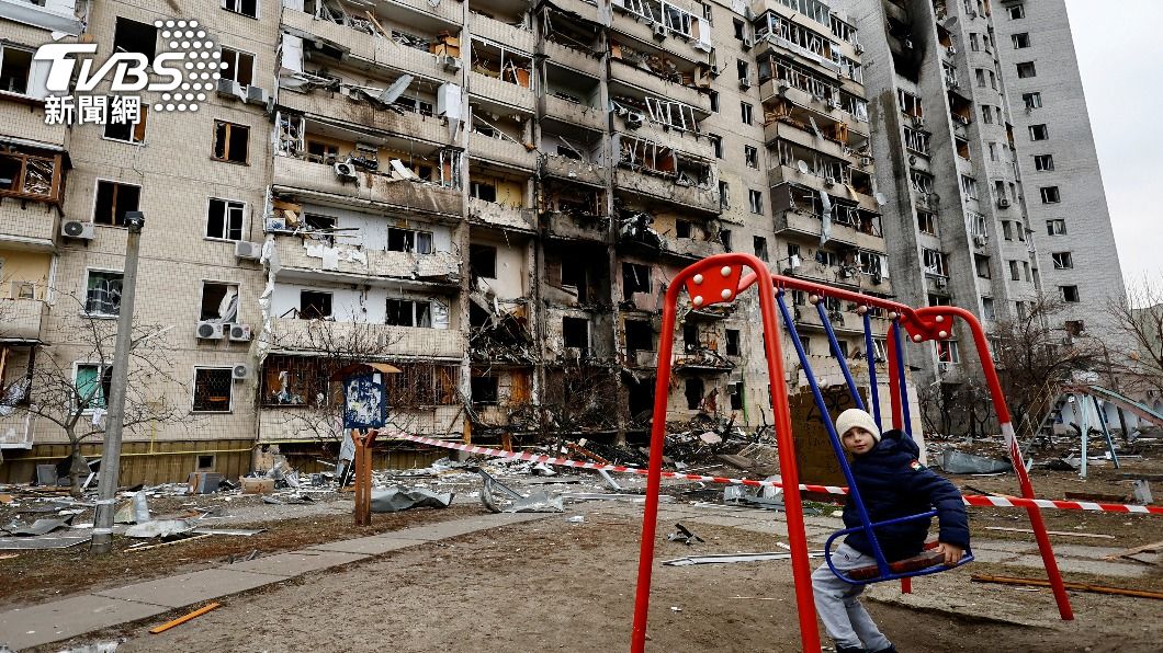 2月俄烏開戰後，一名盪鞦韆的小男孩正在被俄軍轟炸成廢墟的公寓旁玩耍。（圖／達志影像路透社）