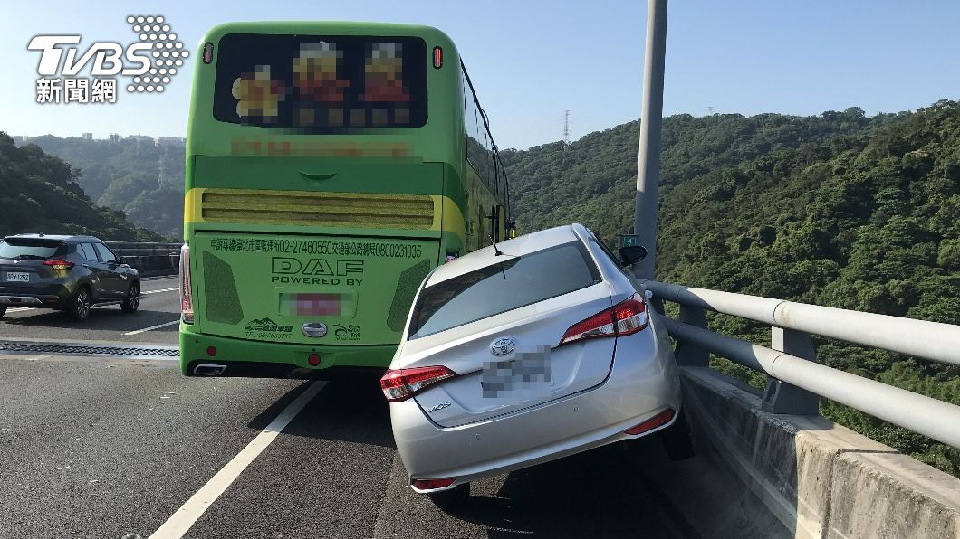 轎車卡在護欄與遊覽車中間。（圖／TVBS）