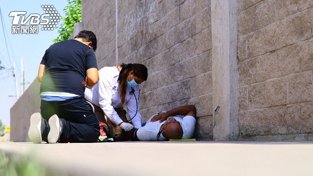 墨西哥華雷斯城的熾熱高溫下，醫護人員為街角邊為中暑倒地的患者進行救治。（圖／達志影像路透社）