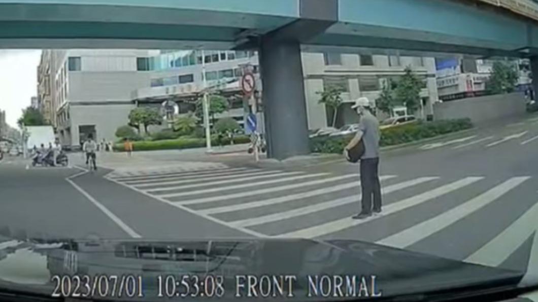 一名駕駛開車行經台北市街頭時，遭路人「呆站斑馬線」阻擋。（圖／翻攝自《記者爆料網》）