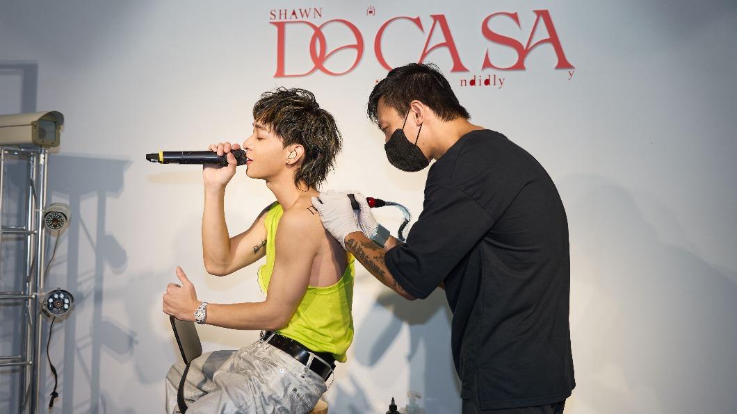 尚融（左）在記者會上一邊刺青一邊唱歌，將新專輯名稱烙印在身上。（圖／索尼音樂提供）
