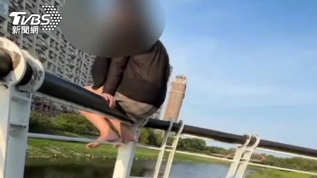 女子因為心情不好坐在2層樓高的堤岸步道欄杆上。（圖／TVBS）