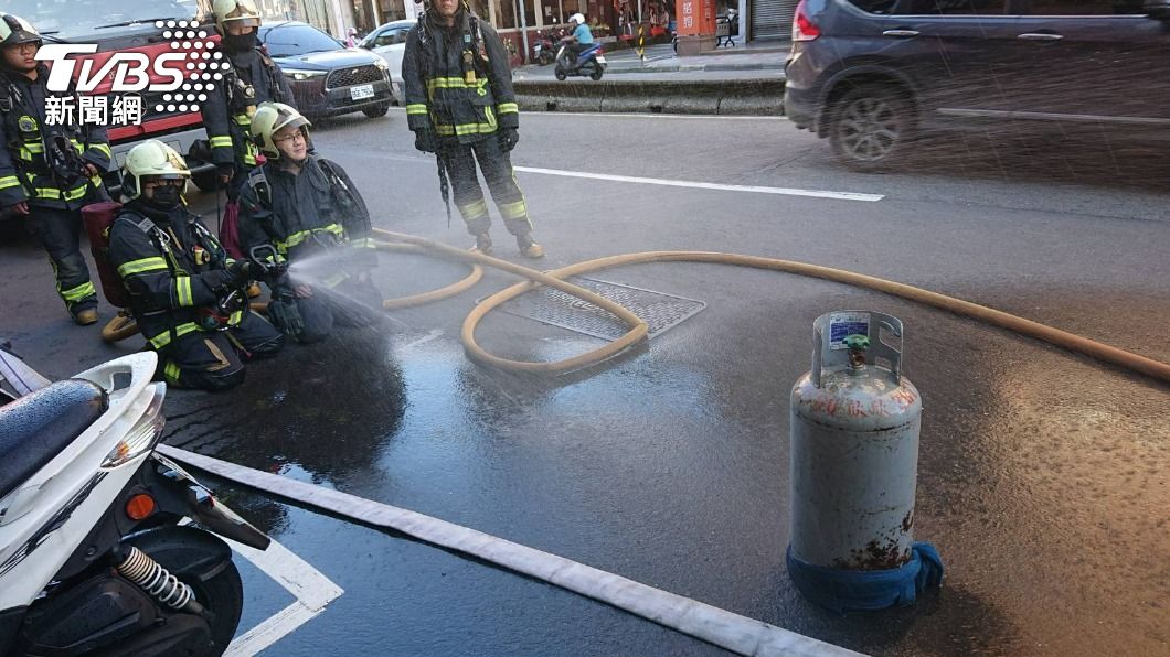 消防人員對著瓦斯鋼瓶灑水。（圖／TVBS）