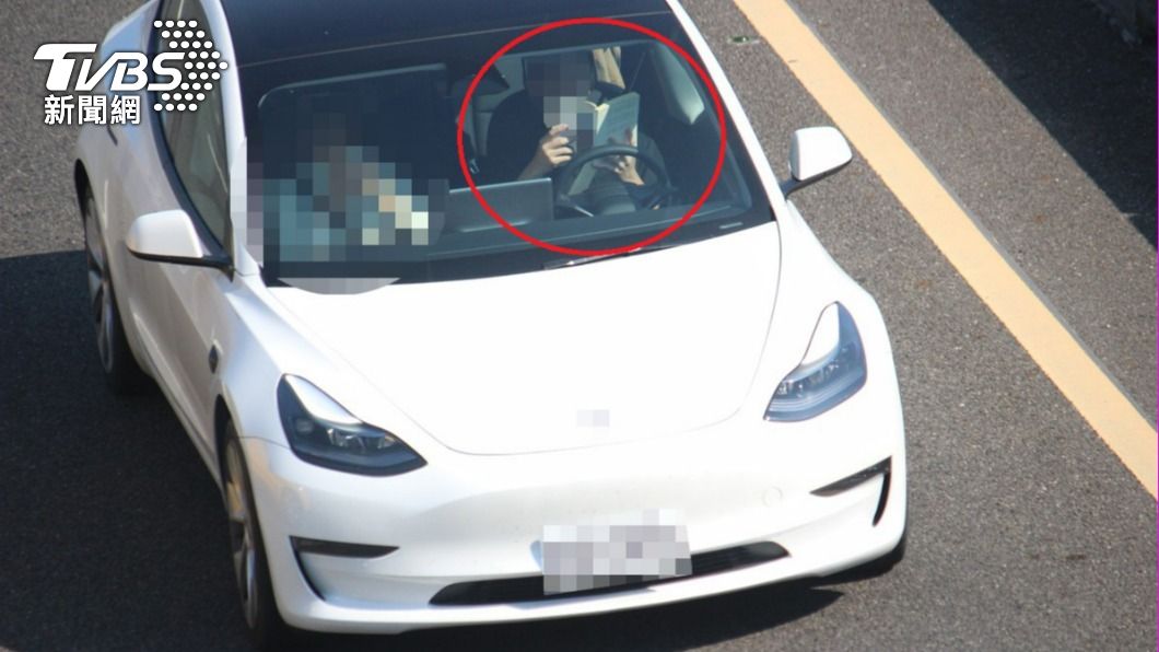 A driver appeared absorbed in his book while driving on the freeway. (TVBS News) Man fined for reading book while driving on freeway