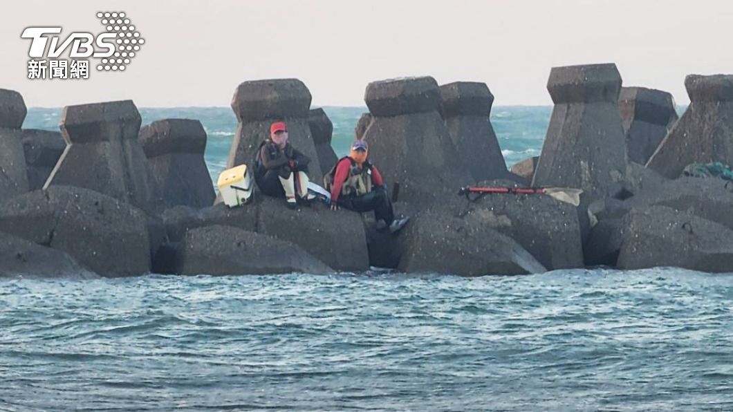 兩名釣客因漲潮迷失回去的路，無奈坐在消波塊上等待救援。（圖／TVBS）
