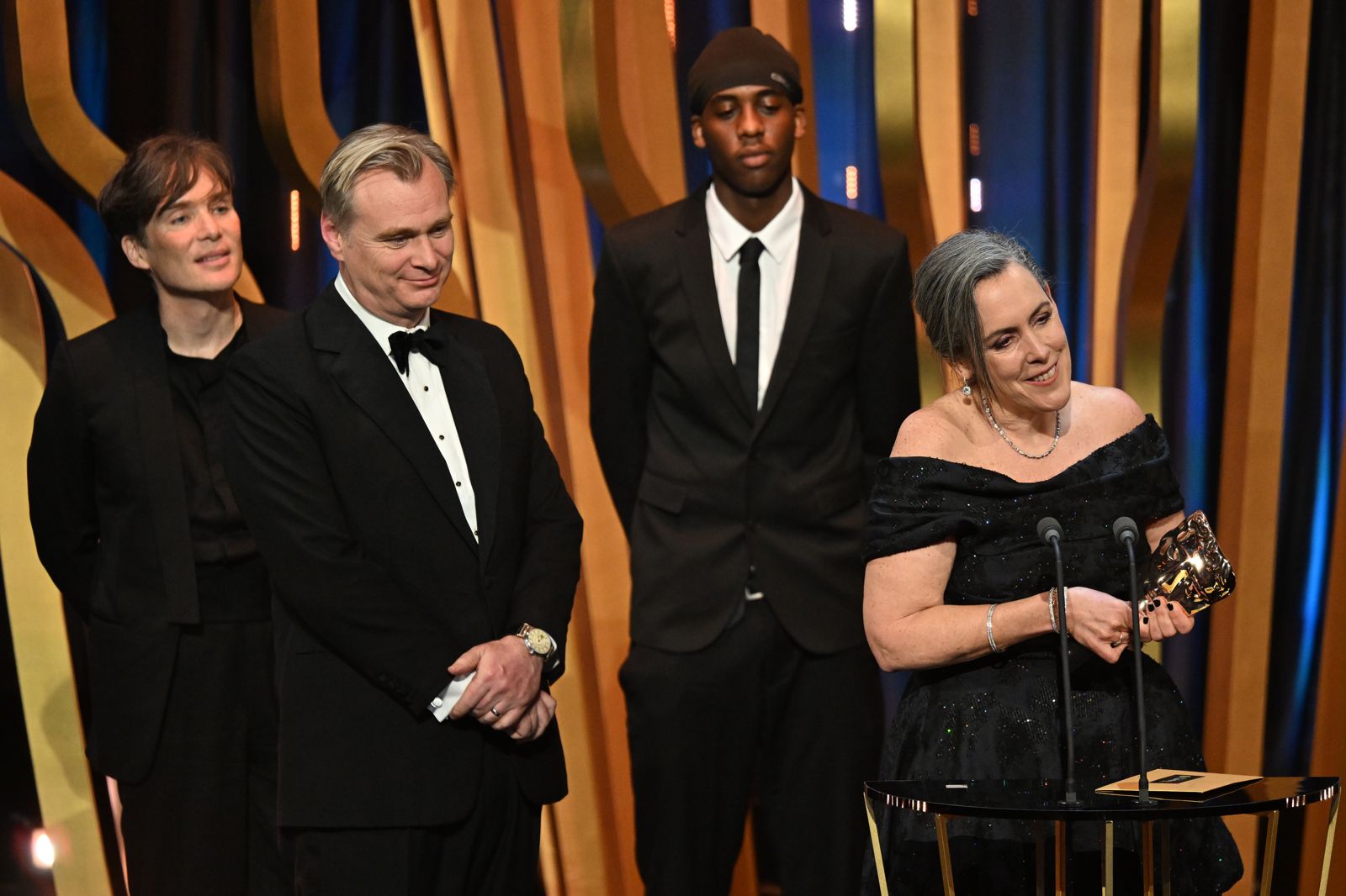 席林墨菲（左起）、導演克里斯多福諾蘭、惡作劇的網紅、製片艾瑪湯瑪斯，一起站在英國影藝學院電影獎舞台上，領取最佳影片。（Getty Images for BAFTA提供）