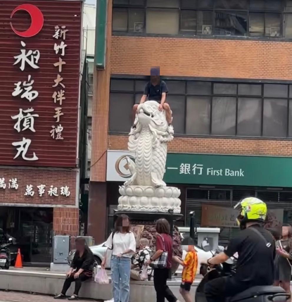 一名男子疑似攀爬到龍鯉石雕的頂端。（圖／翻攝自臉書）