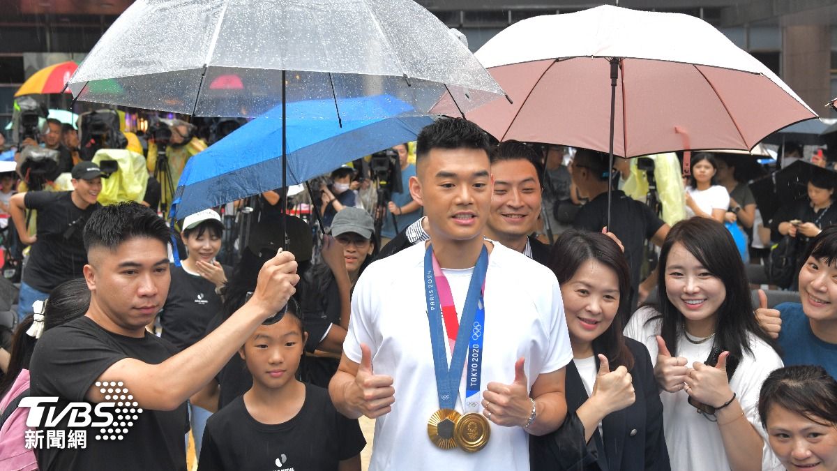 羽球雙打好手王齊麟今天舉辦見面會，儘管下大雨，仍有不少球迷參加，工作人員幫王齊麟撐傘。（圖／胡瑞麒攝）