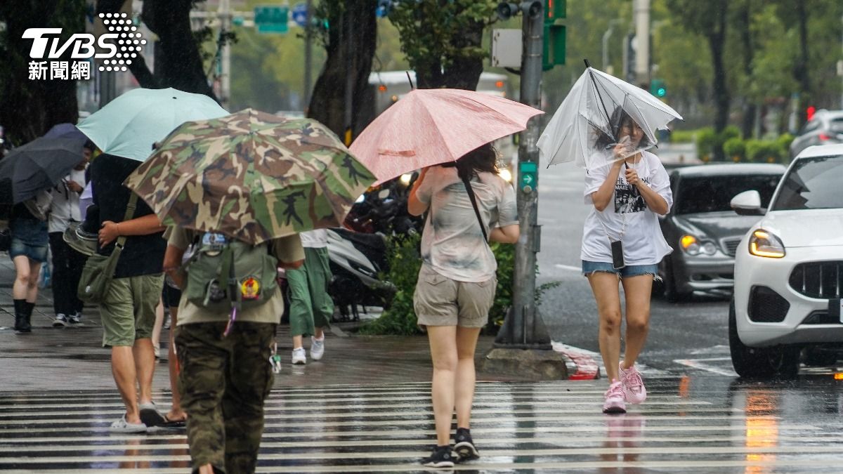 颱風山陀兒來襲，北部街頭有民眾抓緊手中雨傘，以免被強陣風吹翻。（圖／中央社）