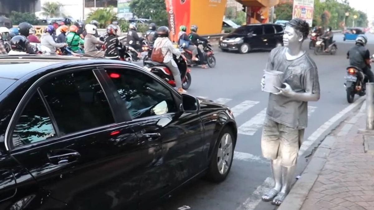 「銀人們」時常赤腳站在路口，向來往的車輛乞討零錢。圖非當事人（翻攝自frengki pasaribu YT）