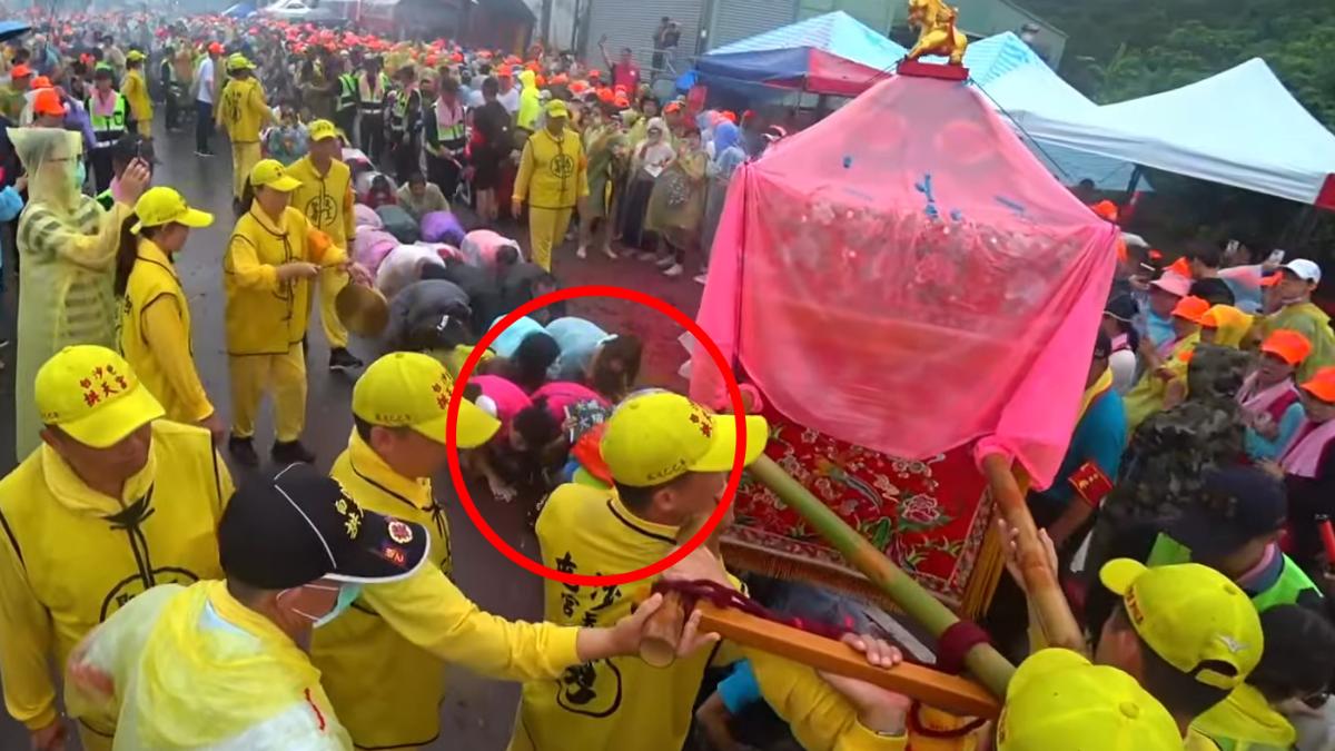 女子持「大罷免大成宮」旗子鑽轎底，隨後媽祖神轎轉向繞過人群離開。（圖／白沙屯媽祖網路電視台YT）