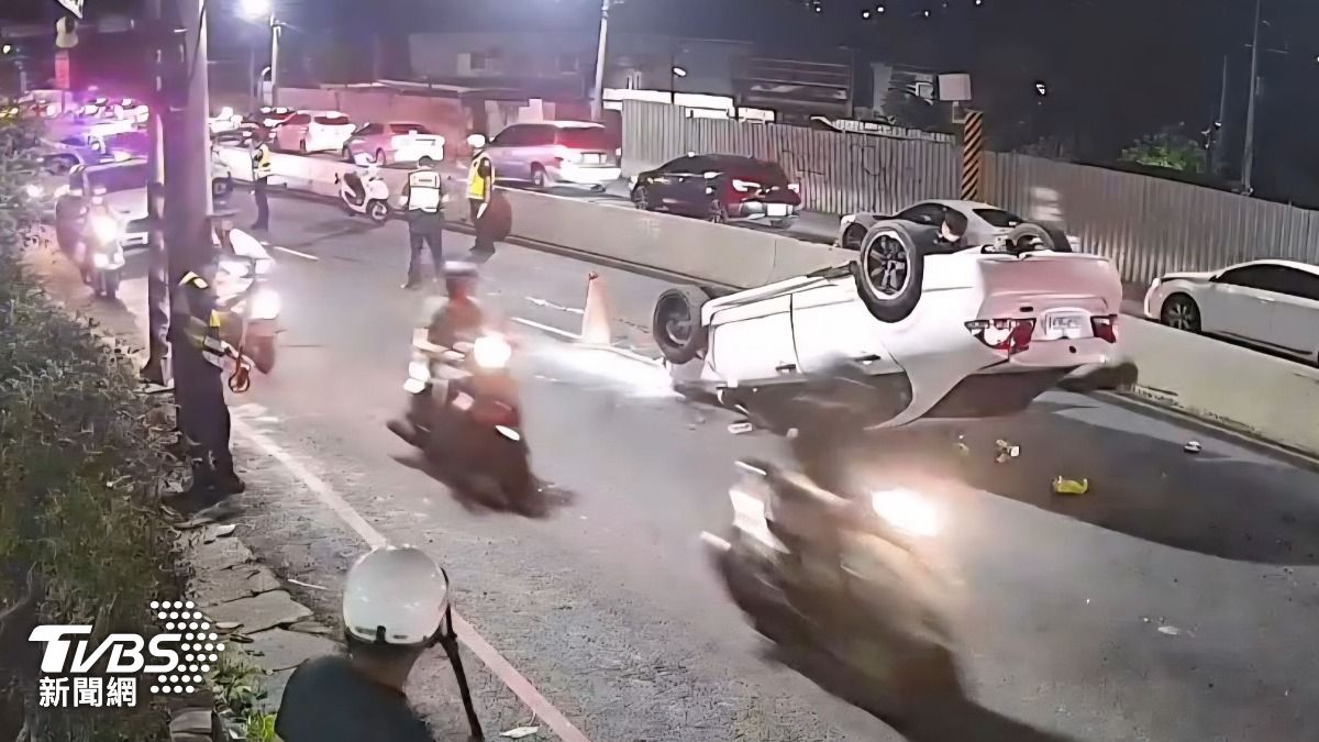 白色轎車撞擊外側路肩交通號誌桿後翻覆，翻轉成逆向四輪朝天。(圖／民眾提供）