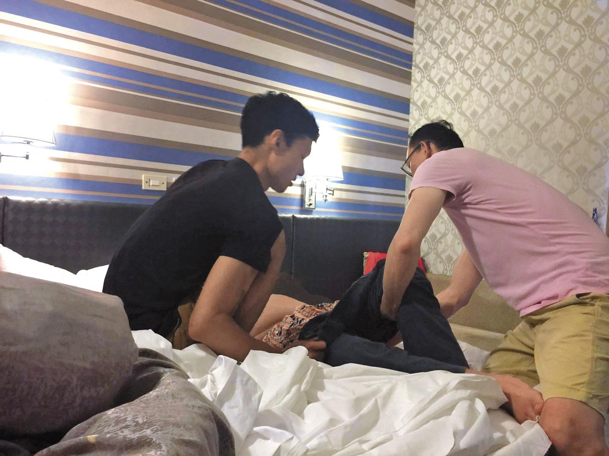 1個月前,周元大(左)初次提供性服務前,和「手天使」志工一起協助將行動不便的服務對象移動到床上。(手天使提供)